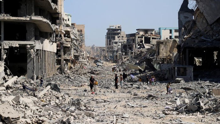 Palestinians walk among rubble following Israeli forces withdrawal from the area, amid a ceasefire between Israel and Hamas in Gaza, in Gaza City October 11, 2025. REUTERS/Ebrahim Hajjaj