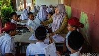 Siswa siswi tampak bersemangat mendengarkan penjelasan guru. Meski belajar dihalaman rumah warga mereka tetap antusias.