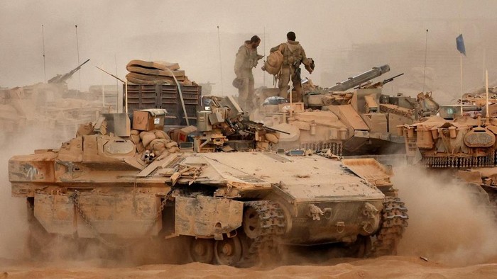 An Israeli army infantry-fighting vehicle (IFVs) deploys next to main battle tanks at a position along the Israel-Gaza border fence on October 10, 2025. Gazas civil defence agency said October 10 that Israeli forces have begun pulling back from parts of the territory, particularly in Gaza City and Khan Yunis. Israeli prime ministers office said that the government had 