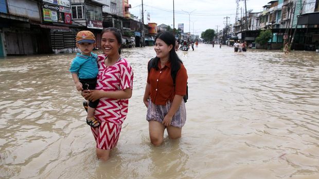 Warga melintasi banjir di Kecamatan Medan Labuhan, Medan, Sumatera Utara, Minggu (12/10/2025). Curah hujan yang tinggi di Kota Medan menyebabkan sungai Deli meluap hingga mengakibatkan jalan dan pemukiman warga terendam banjir. ANTARA FOTO/Yudi Manar/agr