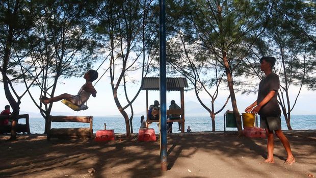 Wisatawan bermain ayunan di tepi Pantai Pulau Santen, Banyuwangi, Jawa Timur, Minggu (12/10/2025). Kontribusi sektor pariwisata terhadap produk domestik bruto (PDB) nasional tercatat naik dari 3,9 persen pada 2023 menjadi 4 persen pada 2024, dan ditargetkan mencapai 8 persen pada 2029. ANTARA FOTO/Budi Candra Setya/tom.