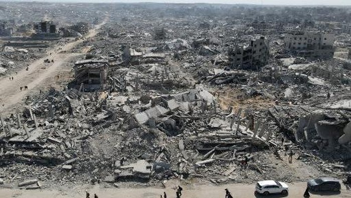 In this aerial view, People walk amid the destruction in Gaza City in the northern Gaza Strip on October 11, 2025, a day after a ceasefire took effect. Israel declared a ceasefire in Gaza and began to pull back its forces on October 10, as tens of thousands of exhausted Palestinians made their way back to their devastated homes. (Photo by AFP)