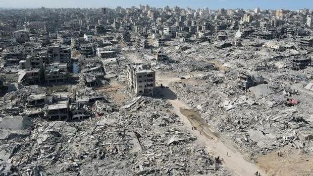 In this aerial view, People walk amid the destruction in Gaza City in the northern Gaza Strip on October 11, 2025, a day after a ceasefire took effect. Israel declared a ceasefire in Gaza and began to pull back its forces on October 10, as tens of thousands of exhausted Palestinians made their way back to their devastated homes. (Photo by AFP)