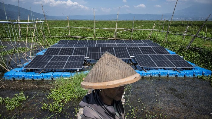 Petani menggunakan perahunya melintas di dekat panel surya yang terpasang di Pembangkit Listrik Tenaga Surya (PLTS) Terapung Rawa Pening, Desa Kesongo, Tuntang, Kabupaten Semarang, Jawa Tengah, Minggu (12/10/2025). Pemerintah Desa Kesongo bersama Politeknik Negeri Semarang (Polines) melalui program Smart Farming berbasis PLTS Terapung Rawa Pening mengembangkan sistem pengairan cerdas berbasis energi surya berkapasitas 20 kWp yang memanfaatkan rangkaian Pompa Air Tenaga Surya (PATS) untuk mengairi sekitar 10 - 15 hektare lahan pertanian sehingga menjadi solusi berkelanjutan bagi petani, terutama saat musim kemarau ketika permukaan air di Danau Rawa Pening mulai surut. ANTARA FOTO/Aprillio Akbar/agr