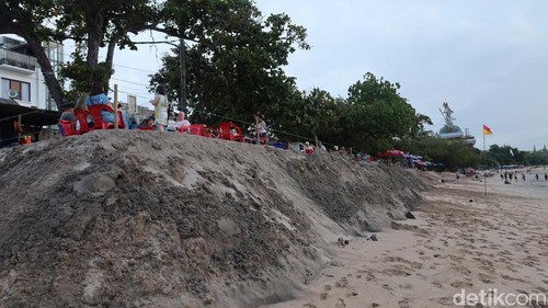 Para wisatawan sedang menikmati sore di depan kios pedagang di atas tebing pasir bekas abrasi, Sabtu (11/10/2025).