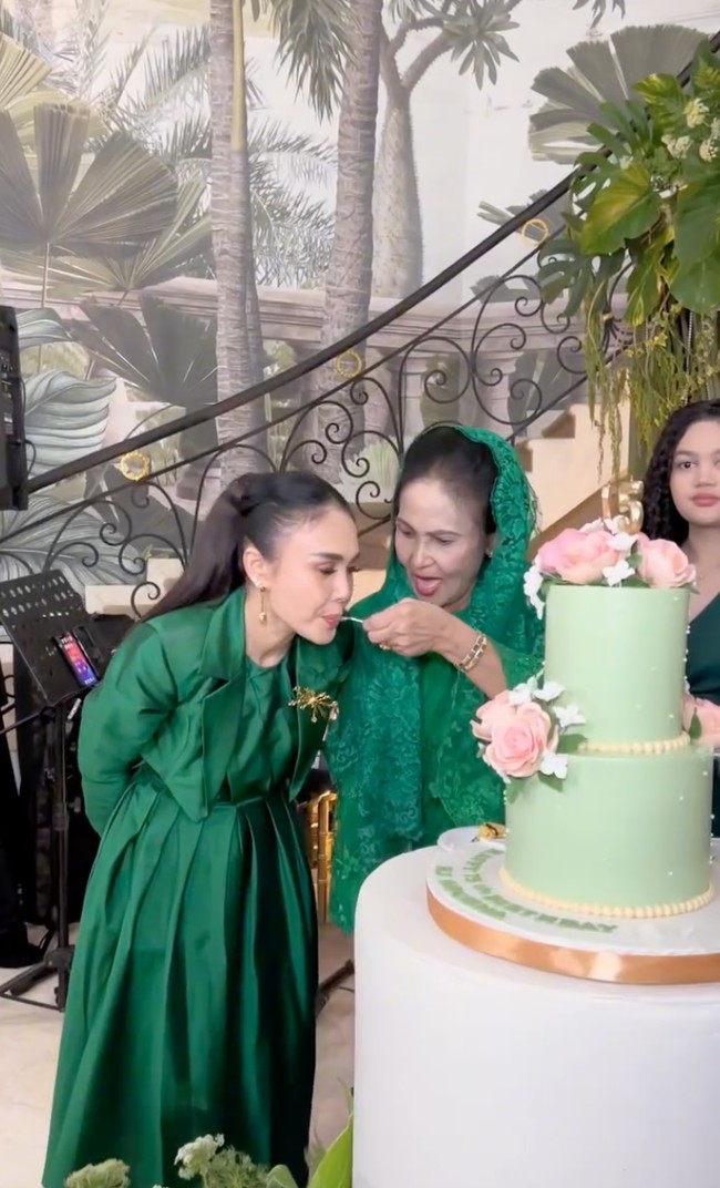 Yuni Shara memilih gaya yang lebih formal dengan long dress berpotongan trench coat dan detail ikat pinggang. Sentuhan bros emas di dada menambah kesan berkelas sekaligus mempercantik tampilannya. Foto: Instagram/@krisdayantilemos