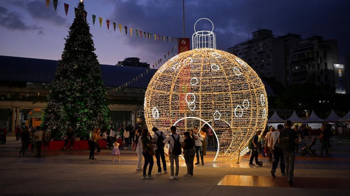 People pose with Christmas decorations in a public square as the holiday season officially begins since  Venezuela's President Nicolas Maduro announced that Christmas celebrations would start in October, two months ahead of the traditional season, in Caracas, Venezuela October 1, 2025. REUTERS/Gaby Oraa