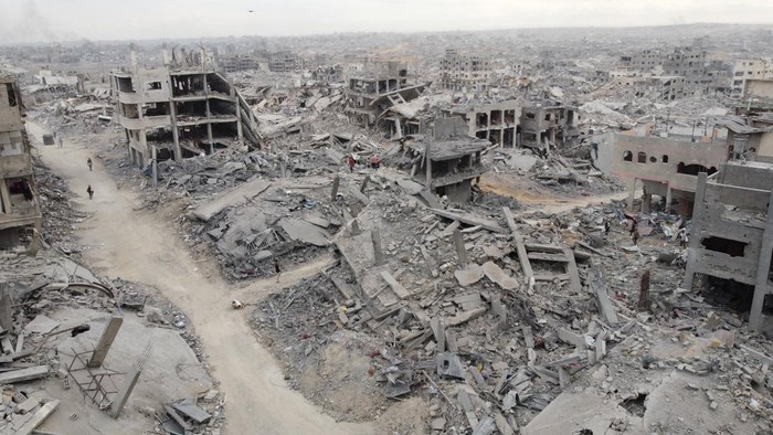 A drone view shows Palestinians walking past rubble following the withdrawal of the Israeli forces from the area, amid a ceasefire between Israel and Hamas in Gaza, in Gaza City, October 12, 2025. REUTERS/Dawoud Abu Alkas