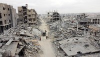 Warga terlihat berjalan di antara puing-puing bangunan di pusat Kota Gaza setelah serangan. Banyak wilayah kini nyaris tak bisa dikenali lagi. Foto: REUTERS/Dawoud Abu Alkas