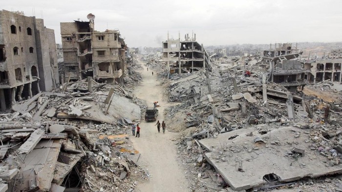 A drone view shows Palestinians walking past rubble following the withdrawal of the Israeli forces from the area, amid a ceasefire between Israel and Hamas in Gaza, in Gaza City, October 12, 2025. REUTERS/Dawoud Abu Alkas REFILE - QUALITY REPEAT     TPX IMAGES OF THE DAY