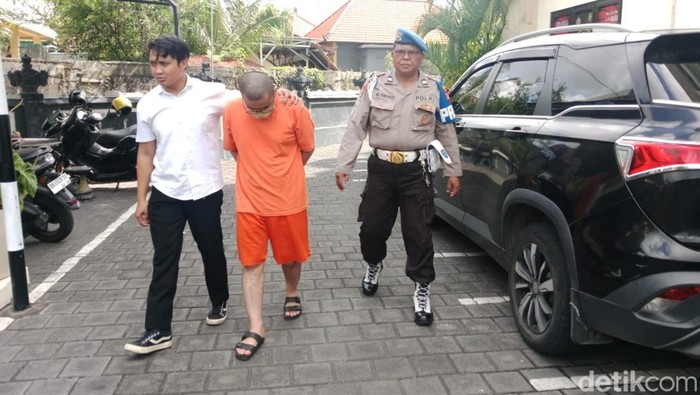 Robby hanya dapat merunduk saat digiring ke ruang tahanan Mapolsek Denpasar Barat, Senin (13/10/2025). (Aryo Mahendro/detikBali).