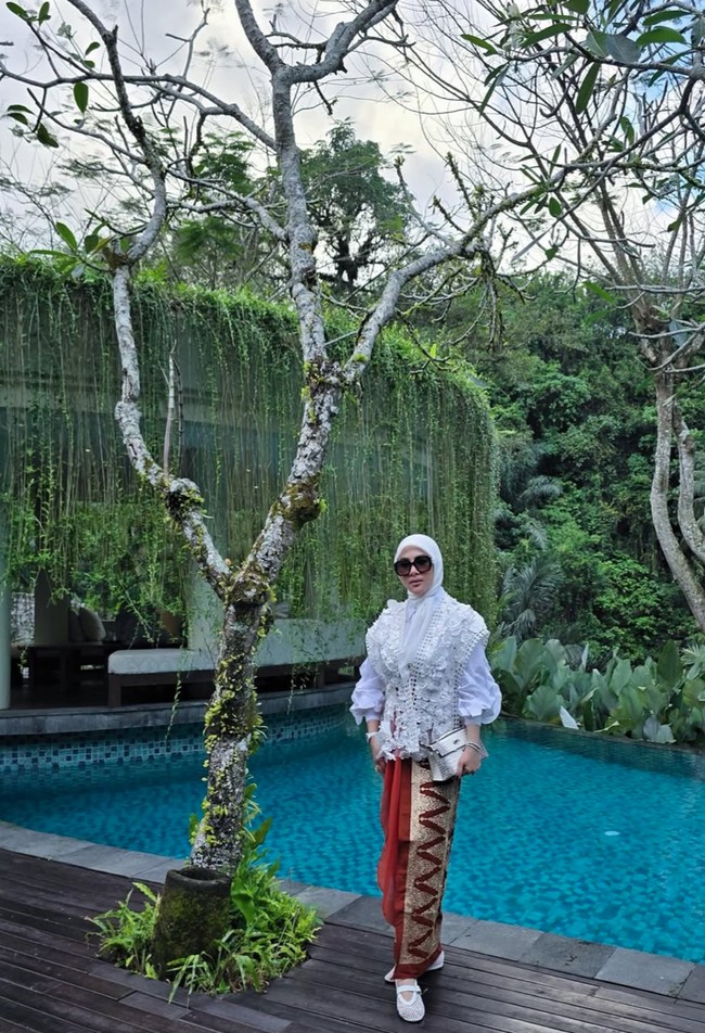 Syahrini memilih atasan lengan balon panjang yang dipadukan dengan vest senada dengan detail floral 3D. Ia juga melengkapi penampilannya dengan sepatu dan hijab putih. Foto: Instagram/@princessyahrini