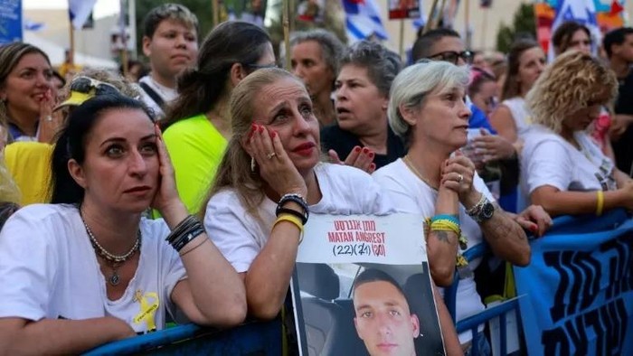 Warga Israel di Alun-alun Sandera Tel Aviv memegang foto sandera yang masih ditahan di Gaza saat menunggu pembebasan mereka oleh Hamas pada 13 Oktober.(AFP/Menahem KAHANA)