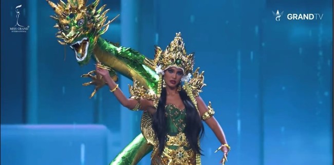 Crown-nya memukau dengan bentuk menyerupai mahkota kerajaan laut, dihiasi batu kristal dan detail ukiran menyerupai ombak dan sisik naga. Dari mahkota itu menjuntai untaian manik panjang berwarna keemasan, menambah kesan elegan dan magis. Foto: Instagram/@vinanggisitorus