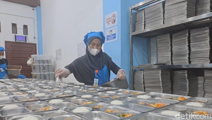 Relawan SPPG Prabumulih menempatkan lauk pauk di ompreng saji dalam ruang pemorsian dapur MBG. ruang khusus