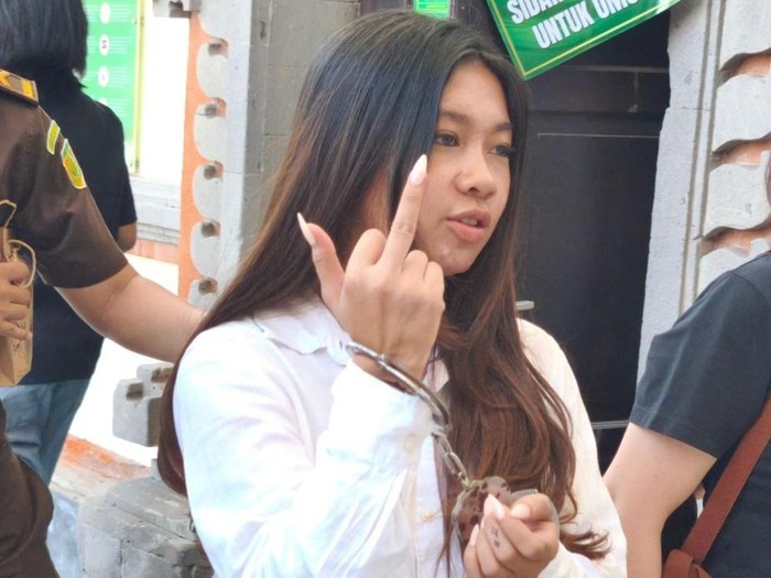 Selebgram Vienna Varella mengacungkan jari tengah ke arah wartawan seusai keluar dari ruang sidang PN Denpasar, Kamis (14/10/2025).
