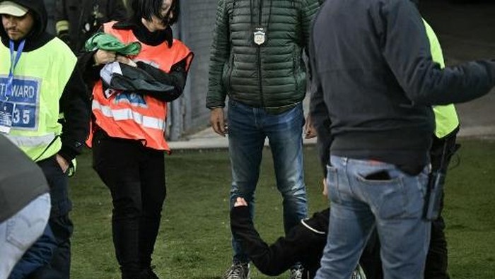 A stewart (L)  takes a Palestinian national flag from a fan (R) who wanted to display during the FIFA World Cup 2026 Group I qualification football match between Italy and Israel, at the the Bluenergy Stadium in Udine northeastern Italy, on October 14, 2025. (Photo by Stefano RELLANDINI / AFP)