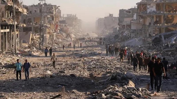 Palestinians walk through a damaged neighborhood in the aftermath of an Israeli operation, after Israel’s government ratified a ceasefire with Hamas, in Gaza City October 10, 2025. (Reuters)