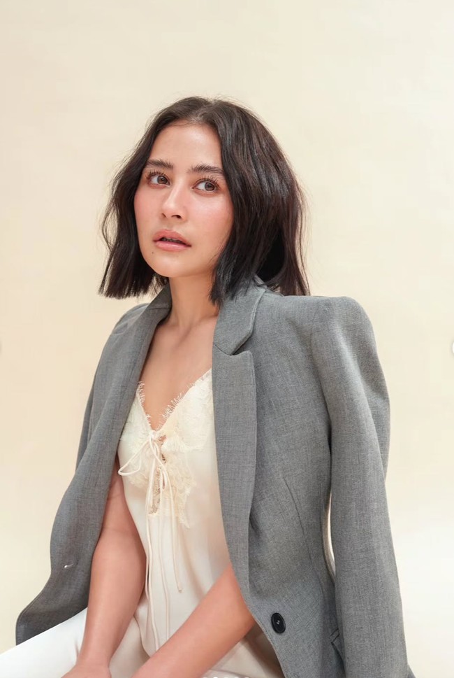 Untuk pemotretan kali ini Prilly mengenakan makeup yang ringan dan natural, menonjolkan pesona wajah aslinya. Kulitnya terlihat segar dengan efek dewy, dilengkapi rona pipi lembut dan lipstik nude yang natural. Riasan mata dibuat minimalis, hanya mempertegas bulu mata agar tetap terlihat hidup tanpa berlebihan. Foto: Instagram/@prillylatuconsina96