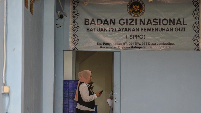 Dua orang jurnalis berjalan di depan fasilitas Satuan Pelayanan Pemenuhan Gizi (SSPG) Dapur Panyandaan, Cisarua, Kabupaten Bandung Barat, Jawa Barat, Rabu (15/10/2025). Pemerintah Kabupaten Bandung Barat menutup sementara SPPG Panyandaan yang diduga 