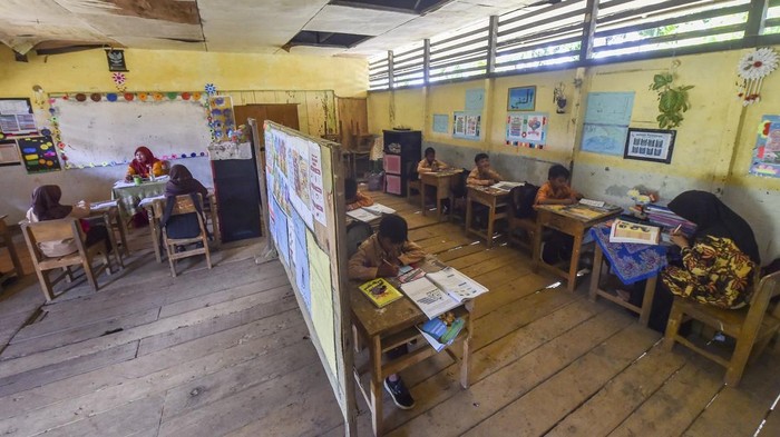 Guru kelas V (kanan) dan kelas VI (kiri) mengajar di ruang kelas yang disekat menggunakan tripleks di SDN 94 Lagan Ulu, Geragai, Tanjung Jabung Timur, Jambi, Kamis (16/10/2025). Sekolah yang saat ini memiliki 37 murid di salah satu perkampungan tua di Tanjung Jabung Timur itu dalam kondisi rusak pada plafon dan lantai sehingga membahayakan guru dan siswa, serta telah 33 tahun lebih melakukan kegiatan belajar mengajar dengan cara disekat untuk empat rombongan belajar (rombel). ANTARA FOTO/Wahdi Septiawan/nz.