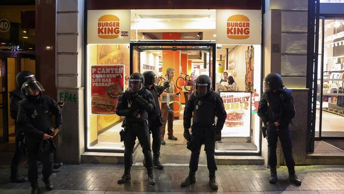 People walk past police officers guarding a McDonald's restaurant during a general strike called by Spanish unions in solidarity with Palestinians in Gaza, in Madrid, Spain, October 15, 2025. REUTERS/Violeta Santos Moura