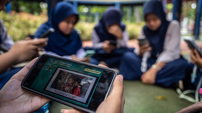 Pelajar memanfaatkan akses internet publik (JakWiFi) milik Pemprov DKI Jakarta untuk belajar di Taman Puring, Jakarta, Kamis (16/10/2025). Pemerintah terus berupaya menciptakan ruang digital yang ramah anak salah satunya melalui penerbitan Peraturan Pemerintah tentang Tunas Anak Indonesia (PP Tunas) yang mendorong peningkatan literasi digital, keamanan siber serta partisipasi anak dalam ekosistem digital yang sehat. ANTARA FOTO/Bayu Pratama S