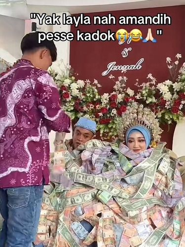Kedua pengantin di Madura ini memakai kalung uang tunai mulai dari pecahan uang Rupiah hingga Dollar. Postingan curhatan tersebut langsung viral di media sosial