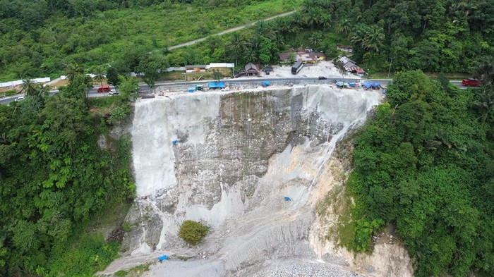 Foto udara pekerja melanjutkan pekerjaan penanganan bahu jalan longsor di Malibo Anai, Padang Pariaman, Sumatera Barat, Kamis (16/10/2025). Balai Pelaksana Jalan Nasional Sumbar melakukan oenanganan longsoran pada ruas jalan nasional akibat banjir bandang tahun lalu, yakni pekerjaan soil nailing (perkuatan lereng) untuk memperkuat struktur tebing, penyemprotan beton di permukaan tebing yang terdampak, serta pada kaki lereng dilakukan pekerjaan proteksi dengan batu grib untuk melindungi lereng dari gerusan arus sungai. ANTARA FOTO/Iggoy el Fitra/nz
