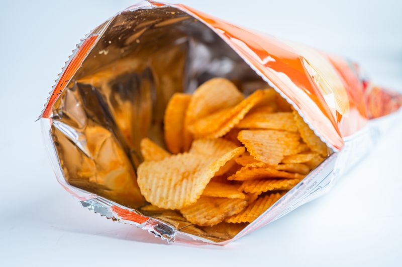 1343300051 Potato chips, delicious BBQ seasoning spicy for crips, thin slice deep fried snack fast food in open bag.
