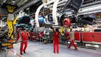 Pekerja memasang panel bodi mobil di lini perakitan Ferrari. Transformasi menuju kendaraan listrik dilakukan tanpa mengorbankan kualitas khas Kuda Jingkrak. Foto: REUTERS/Remo Casilli