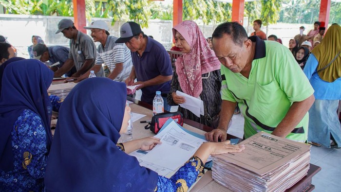 Petugas memverifikasi data warga penerima sertifikat tanah program Pendaftaran Tanah Sistematis Lengkap (PTSL) di Balai Desa Jugosari, Lumajang, Jawa Timur, Jumat (17/10/2025). Badan Pertanahan Nasional (BPN) Lumajang menyerahkan sebanyak 6.000 sertifikat tanah program PTSL tahun 2025 secara bertahap, baik dalam bentuk fisik maupun elektronik, guna mencegah terjadinya penggandaan atau penipuan sertifikat. ANTARA FOTO/Irfan Sumanjaya/foc.