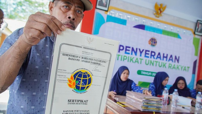 Warga memperlihatkan sertifikat tanah program Pendaftaran Tanah Sistematis Lengkap (PTSL) yang diterimanya di Balai Desa Jugosari, Lumajang, Jawa Timur, Jumat (17/10/2025). Badan Pertanahan Nasional (BPN) Lumajang menyerahkan sebanyak 6.000 sertifikat tanah program PTSL tahun 2025 secara bertahap, baik dalam bentuk fisik maupun elektronik, guna mencegah terjadinya penggandaan atau penipuan sertifikat. ANTARA FOTO/Irfan Sumanjaya/foc.