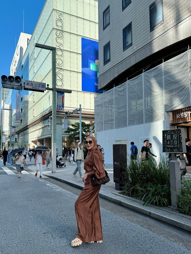 Tampil di jalanan Ginza, Erin mengenakan setelan satin berwarna cokelat karamel yang lembut. Gaya ini dipadukan dengan sandal chunky dan tas bahu klasik, menciptakan look modern sekaligus feminin. Foto: Instagram/@erintaulany