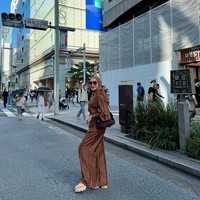 Tampil di jalanan Ginza, Erin mengenakan setelan satin berwarna cokelat karamel yang lembut. Gaya ini dipadukan dengan sandal chunky dan tas bahu klasik, menciptakan look modern sekaligus feminin. Foto: Instagram/@erintaulany
