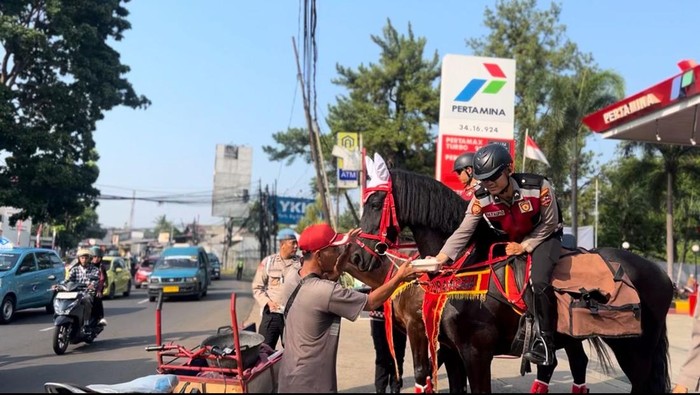 Momen polisi membagikan makanan ke warga dengan menunggangi kuda di Depok, Jawa Barat.