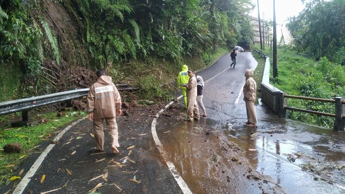 Personel Polsek Baturraden saat mengevakuasi material longsor yang menutup jalan penghubung Desa Karangsalam Lor-Kemutug Lor, Banyumas, Minggu (19/10/2025).