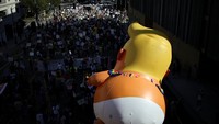 Sebuah balon raksasa bergambar Presiden Trump tampak melayang di atas kerumunan sebagai simbol kritik terhadap kepemimpinan yang dianggap berlebihan dalam kekuasaan. REUTERS/Daniel Cole