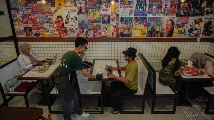 Pramusaji mengantarkan makanan kepada pelanggan di Kedai Kopitiam, Lumajang, Jawa Timur, Minggu (19/10/2025). Badan Penyelenggara Jaminan Produk Halal (BPJPH) mempermudah sertifikasi halal bagi warung makan kecil melalui Program Sertifikasi Halal Gratis (Sehati) untuk mendorong pengusaha dalam percepatan kewajiban sertifikasi halal bagi seluruh produk makanan dan minuman pada tahun 2026. ANTARA FOTO/Irfan Sumanjaya
