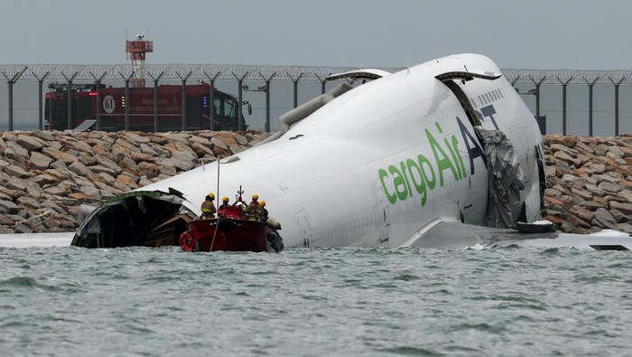 Emergency personnel work near a cargo plane lying partially in the sea after it veered off the runway during landing at Hong Kong International Airport in Hong Kong, China, October 20, 2025. REUTERS/Tyrone Siu