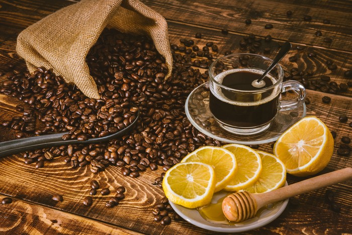 Coffee cup and beans on old kitchen table. Top view with copy space for your text. coffee bag and with sliced u200bu200blemons on wooden table. Black coffee beans.