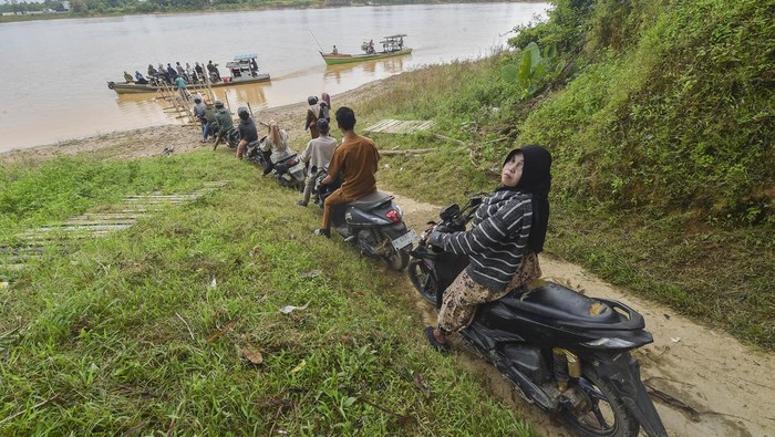 Pengendara sepeda motor dan warga mengantre untuk menyeberangi Sungai Batanghari dari Desa Keranggan menuju Desa Berembang di Sekernan, Muaro Jambi, Jambi, Senin (20/10/2025). Warga setempat menyebutkan, sedikitnya 200 warga Sekernan yang berada di tepi Daerah Aliran Sungai (DAS) Batanghari masih menggunakan perahu untuk menyeberangi sungai terpanjang di Sumatera itu setiap harinya dengan tarif umum Rp7 ribu per motor pulang-pergi (PP) dan Rp5 ribu per motor PP untuk pelajar karena tidak adanya jembatan penghubung. ANTARA FOTO/Wahdi Septiawan/YU