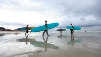 Sejumlah ibu bersiap dengan papan selancar di Pantai Muizenberg, Cape Town, sebelum memulai sesi “terapi laut” dari program Moms on Board. Foto: REUTERS/Esa Alexander