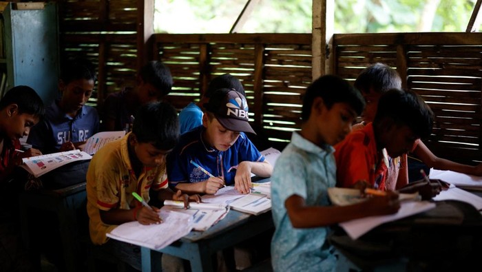 Sekolah Perahu Jadi Harapan Anak-Anak di Negeri yang Selalu Terendam Students read books inside a floating library built on a boat by an NGO named Shidhulai Swanirvar Sangstha, in Bhangura area of Pabna, Bangladesh, September 25, 2025. REUTERS/Mohammad Ponir Hossain