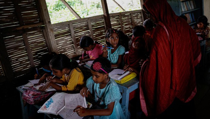 Sekolah Perahu Jadi Harapan Anak-Anak di Negeri yang Selalu Terendam Students read books inside a floating library built on a boat by an NGO named Shidhulai Swanirvar Sangstha, in Bhangura area of Pabna, Bangladesh, September 25, 2025. REUTERS/Mohammad Ponir Hossain