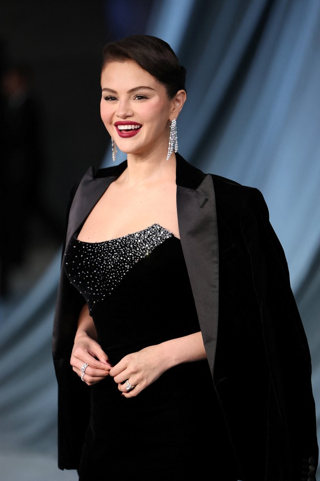 Selena memancarkan pesona klasik khas Old Hollywood lewat gaun hitam glamor bertabur payet berkilau. Dia memadukannya dengan blazer hitam yang disampirkan di bahu, lipstik red wine, serta tatanan rambut updo elegan yang menonjolkan keanggunannya. Foto: REUTERS/Mario Anzuoni