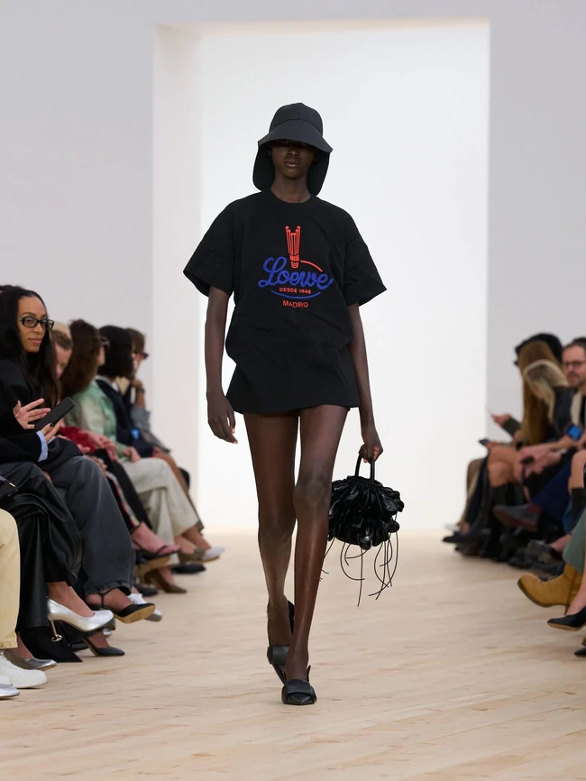 Aksesori menjadi primadona tersendiri. Tas Amazona dengan satu pegangan yang tampak longgar, sepatu loafers berwarna primer yang mengilap, hingga sepatu kitten heels transparan yang dipadukan dengan kaus kaki mini warna-warni—perpaduan eksentrik yang menyegarkan. (Foto: Dok. Loewe)