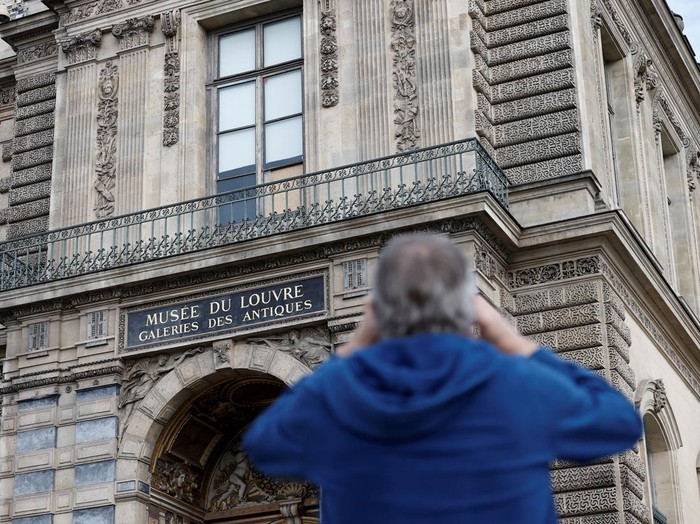 Lokasi Pembobolan Louvre Jadi Daya Tarik Wisata Baru di Paris People take a selfie in front of a broken window protected by a wooden panel at the Louvre Museum as the museum remains closed the day after a spectacular jewel heist by thieves who broke into the landmark by using a crane and smashing an upstairs window, stealing priceless jewelry from an area that houses the French crown jewels before escaping on motorbikes, in Paris, France, October 20, 2025. REUTERS/Benoit Tessier TPX IMAGES OF THE DAY