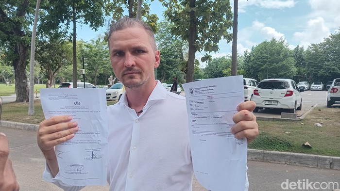 Sergei menunjukkan surat laporan polisi dan hasil visum bekas penganiayaan yang dialaminya, Selasa (21/10/2025).
