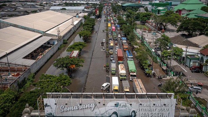 Foto udara sejumlah kendaraan melaju perlahan melewati banjir di jalur utama pantura Semarang-Surabaya, Jalan Kaligawe Raya, Semarang, Jawa Tengah, Rabu (22/10/2025). Menurut data sementara yang dihimpun BPBD Kota Semarang pada Rabu (22/10) pukul 10.00 WIB, setidaknya ada delapan titik jalan raya dan jalan permukiman di Kota Semarang tergenang banjir setinggi sekitar 10-40 sentimeter dampak dari anomali cuaca dengan intensitas hujan tinggi yang melanda pada Selasa (21/10) hingga Rabu (22/10) dini hari, sehingga menyebabkan aktivitas warga dan lalu lintas terganggu. ANTARA FOTO/Aji Styawan/tom.